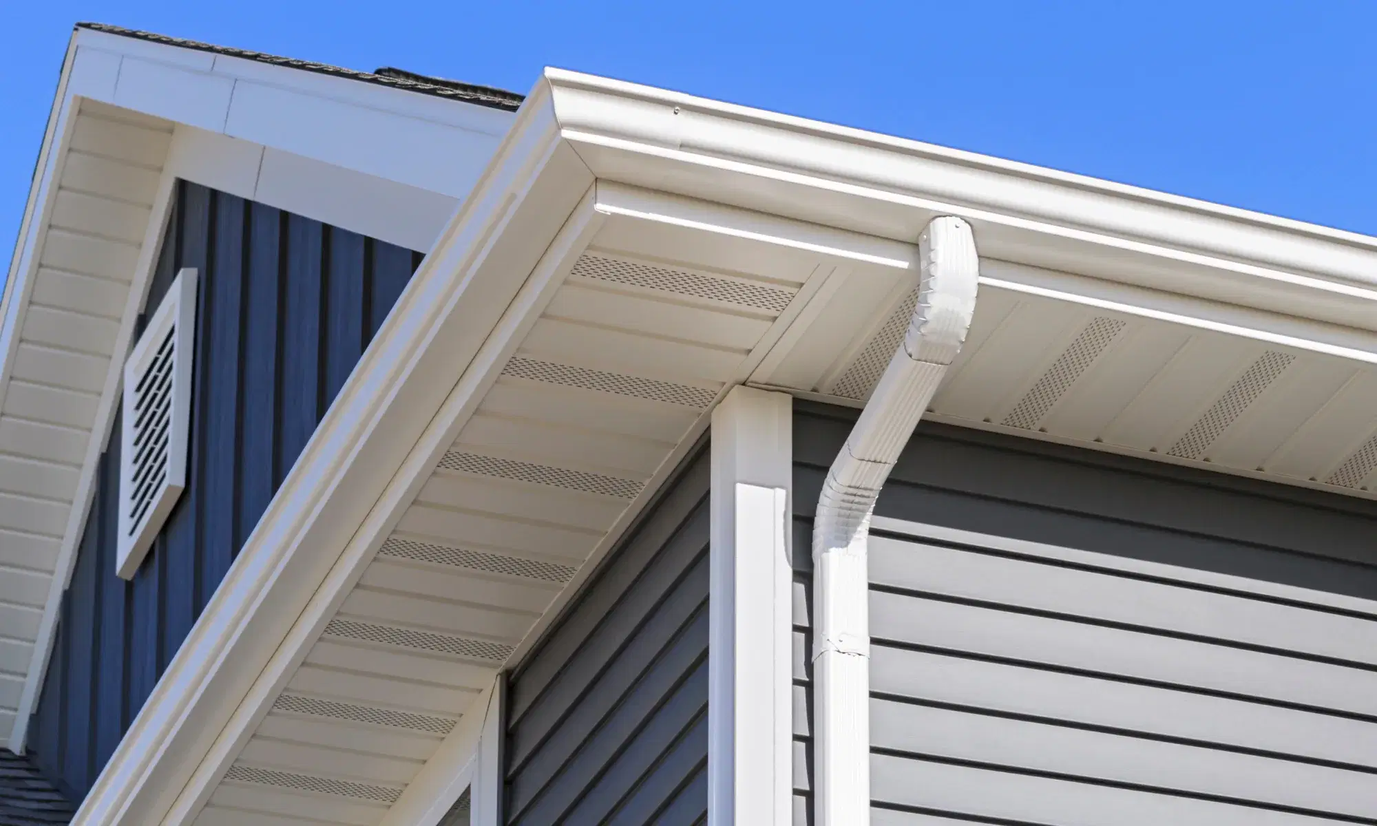 White gutters and downspout installed along a home roofline